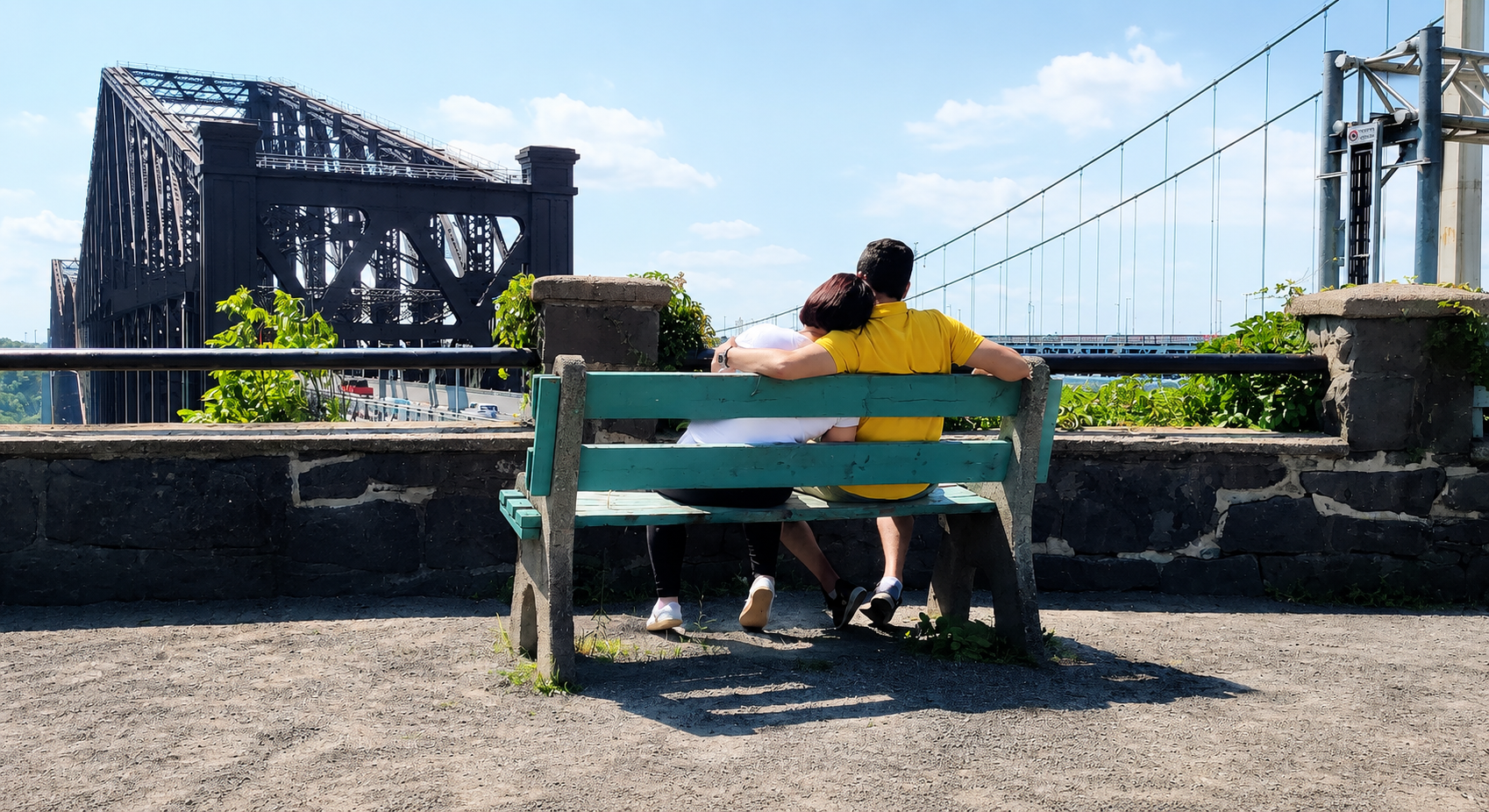 Marjan and Reza sitting on a bench overlooking the Quebec Bridge